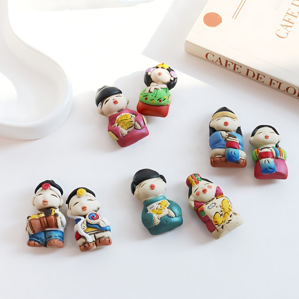 "meta_description": "Charming ceramic magnet depicting traditional couples, a perfect cultural keepsake.",