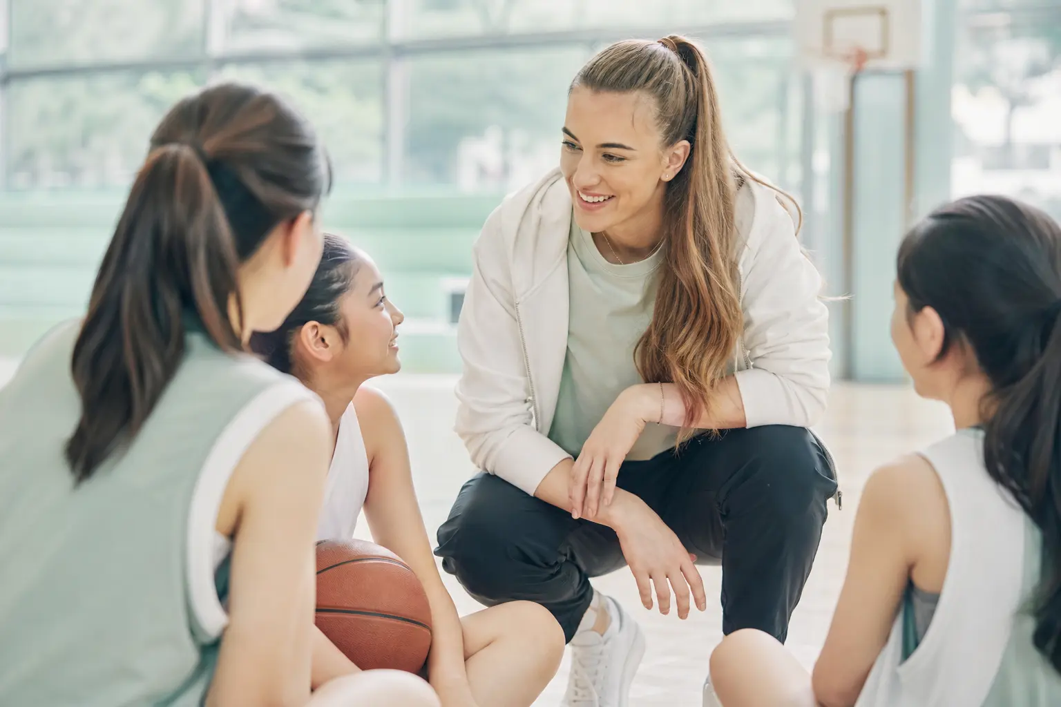 An inspiring image of Sabrina Ionescu interacting with young athletes at a basketball camp, encouraging them to pursue t