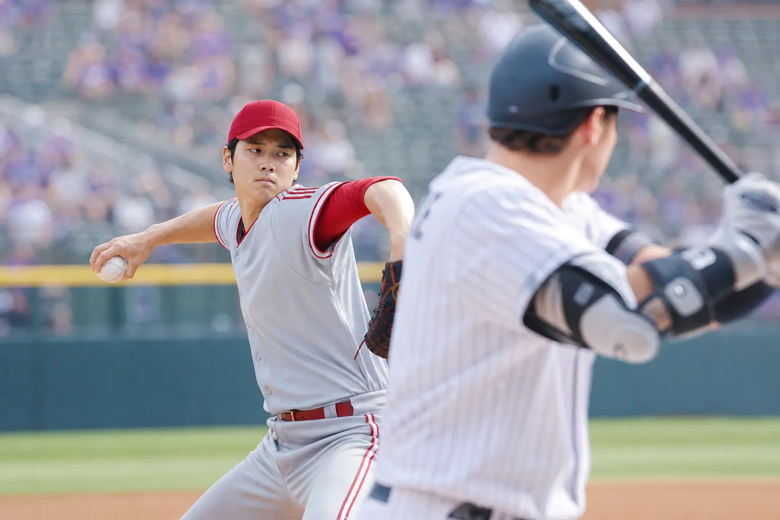 A close-up of a Reds player pitching against a Rockies batter at Coors Field, highlighting the intensity of the matchup.